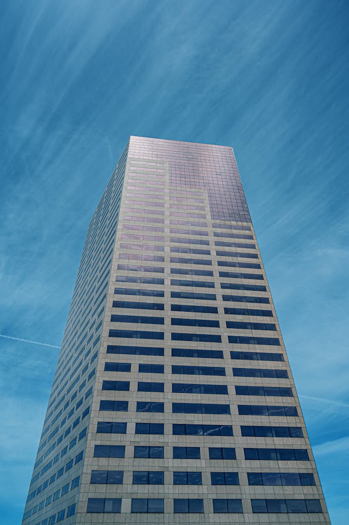 Tall modern skyscraper with a reflective facade against a clear blue sky, showcasing urban architecture.
